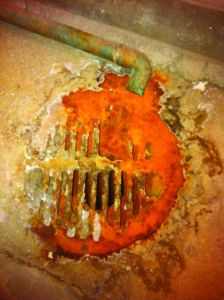 Orange metal drain corroded by acidic condensate.