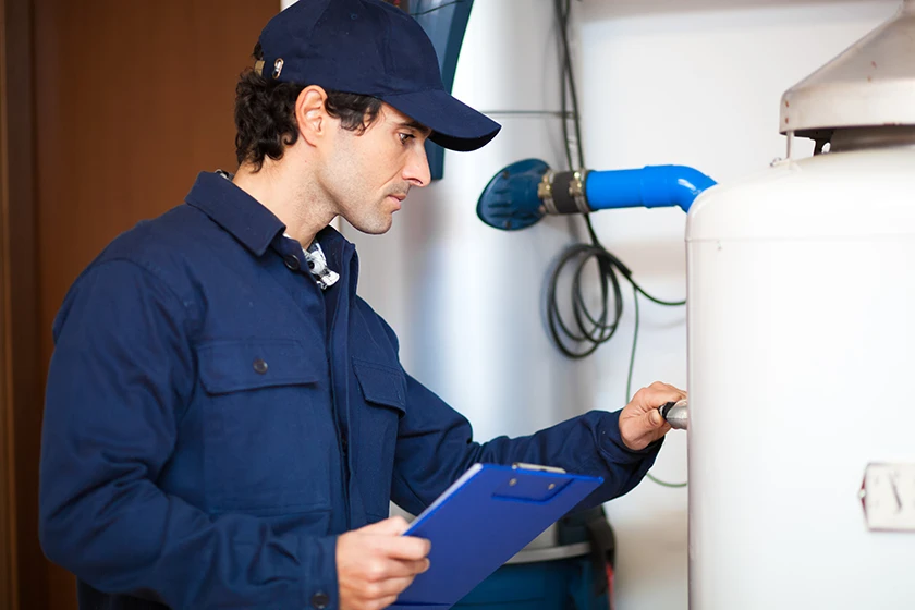 Technician inspecting a gas-fired heating appliance for maintenance and assessing condensate neutralizer needs.