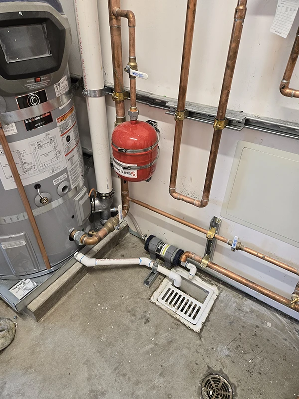 Condensate neutralizer installation protecting plumbing and floor drains from acidic condensate corrosion.